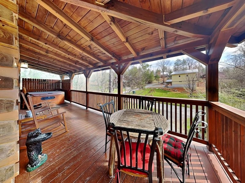 Your private covered deck invites you to unwind with a cozy rocking chair, hot tub, and scenic hillside views—perfect for morning coffee or starlit evening soaks.