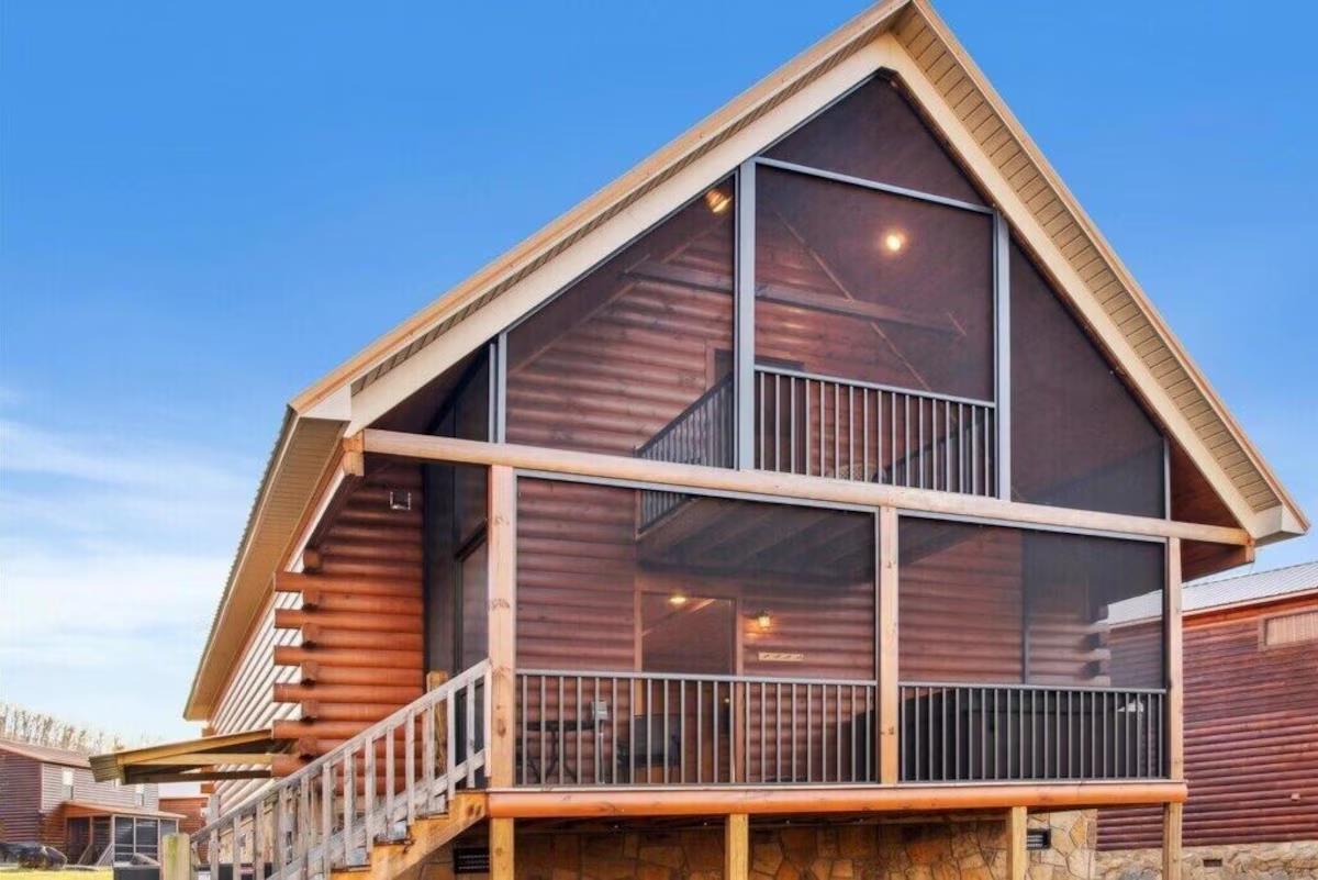 Modern mountain lodge featuring rustic wood siding and expansive glass windows under crisp blue skies.