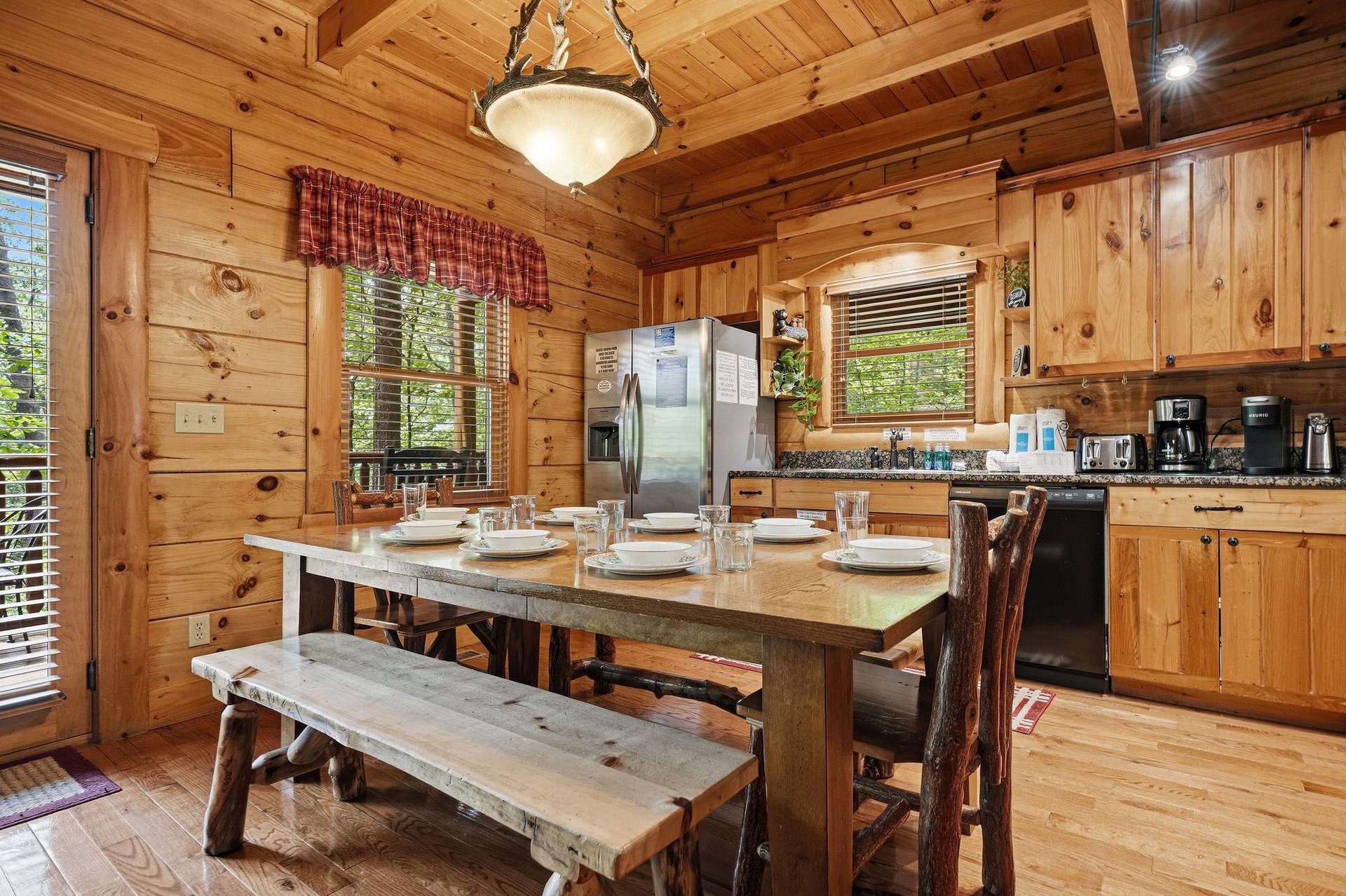 Gather around the handcrafted dining table in your fully equipped cabin kitchen, where rustic wood beams and warm pine walls create a cozy mountain retreat perfect for sharing meals with family and fr