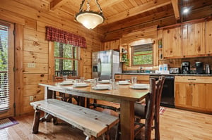 Gather around the handcrafted dining table in your fully equipped cabin kitchen, where rustic wood beams and warm pine walls create a cozy mountain retreat perfect for sharing meals with family and fr