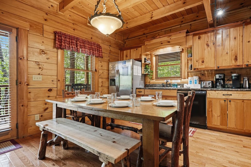 Gather around the handcrafted dining table in your fully equipped cabin kitchen, where rustic wood beams and warm pine walls create a cozy mountain retreat perfect for sharing meals with family and fr