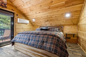Sink into the plaid comfort of your rustic woodpaneled bedroom, where vaulted ceilings and cozy mountain charm invite restful nights and peaceful mornings.