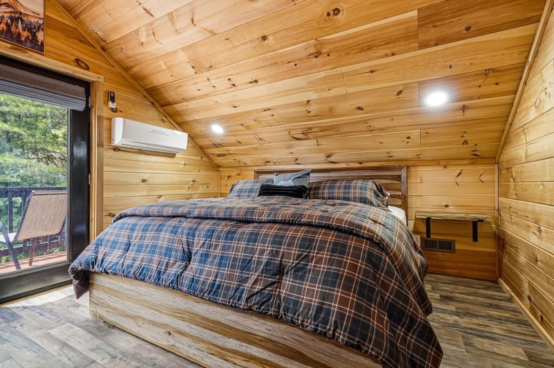 Sink into the plaid comfort of your rustic woodpaneled bedroom, where vaulted ceilings and cozy mountain charm invite restful nights and peaceful mornings.