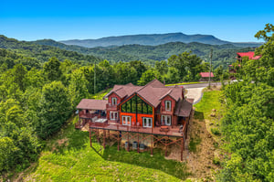 Aerial view of the property showcasing its elevated mountain setting and spacious multilevel design, surrounded by lush forest and distant mountain vistas.