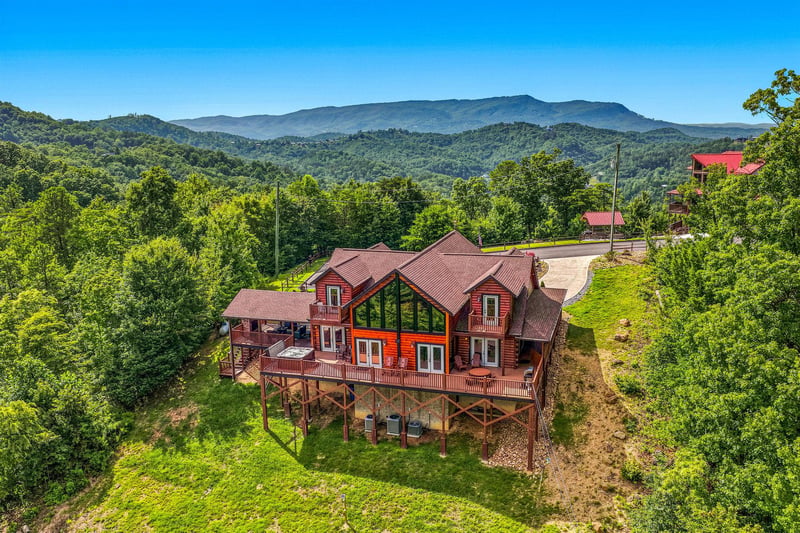 Aerial view of the property showcasing its elevated mountain setting and spacious multilevel design, surrounded by lush forest and distant mountain vistas.