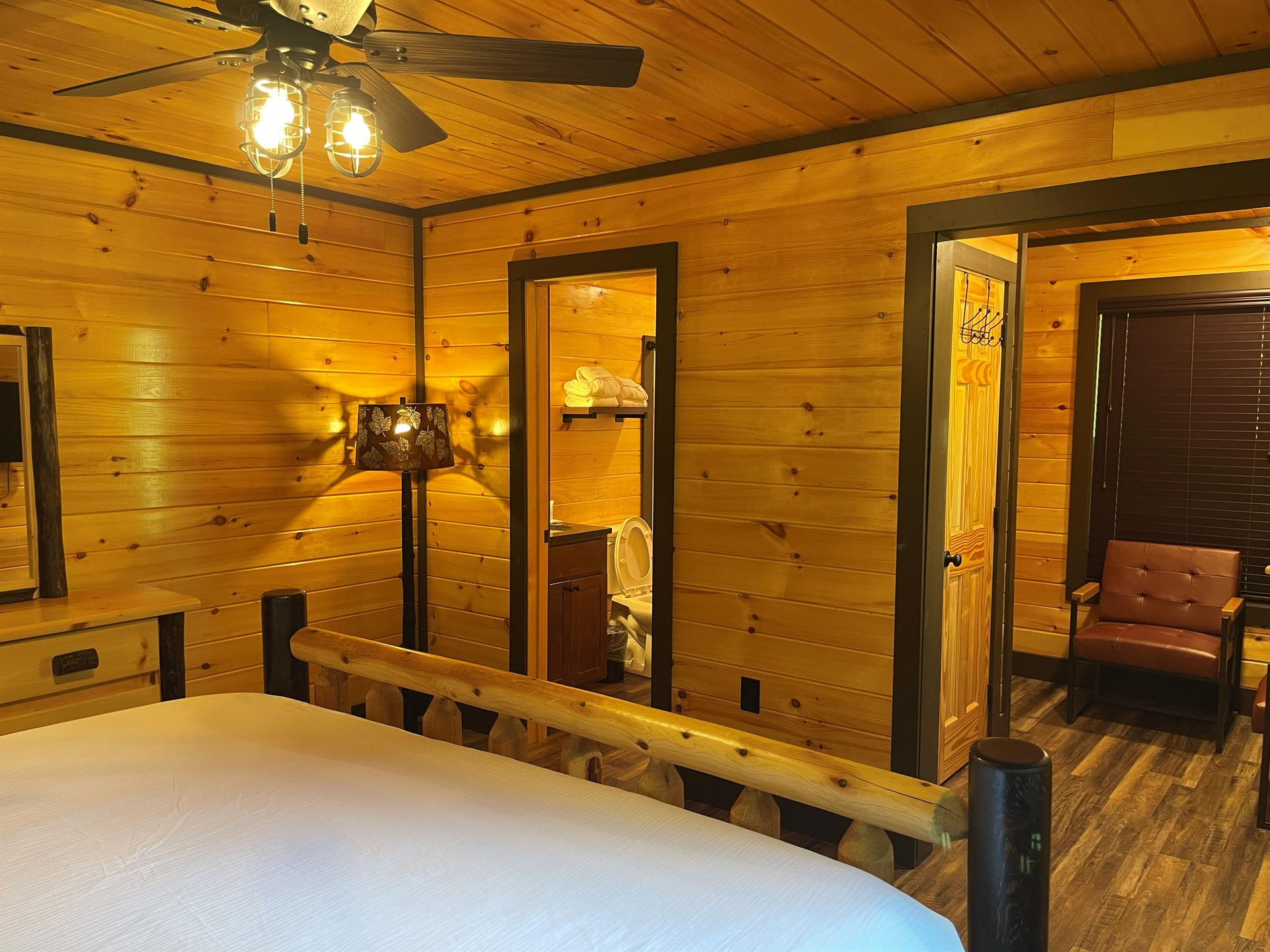 Settle into your cozy bedroom with warm wood paneling and rustic charm. Fresh linens welcome you after a day of adventure, and your private bathroom is just steps away.