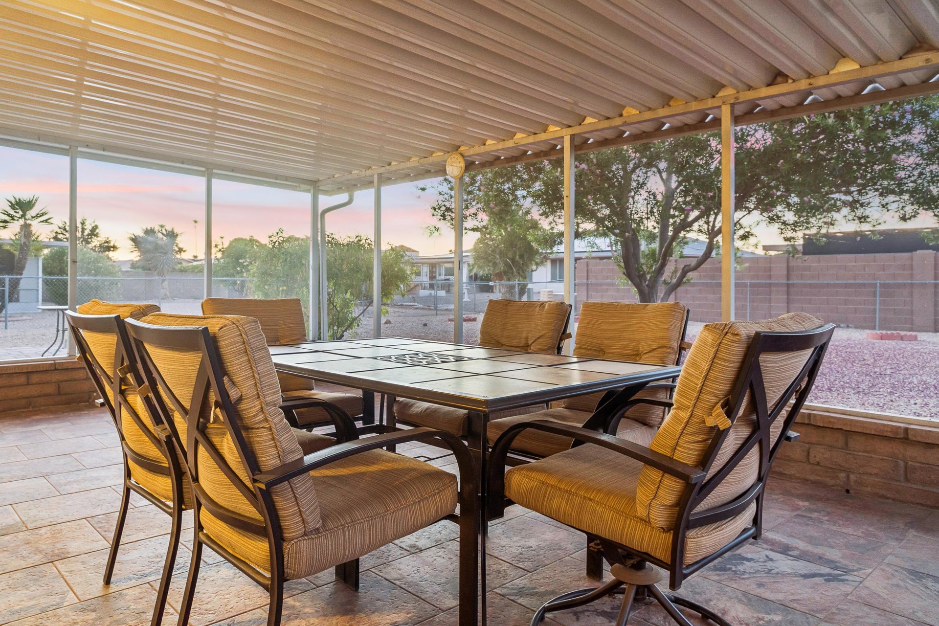 Screened patio with fan, and outdoor dining table and chairs for 6 guests.