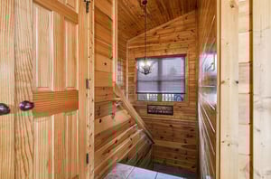 Warm wood paneling creates a cozy mountain retreat atmosphere as you ascend the beautifully crafted staircase.