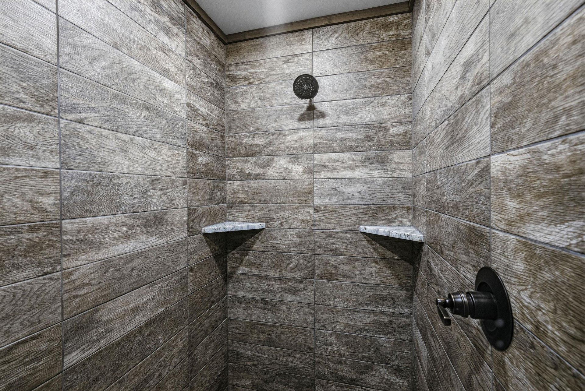 Step into your private rain shower with sleek woodgrain tiling and builtin benches—perfect for unwinding after a day of adventure.