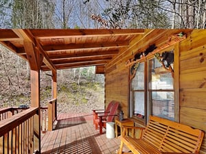 Step out onto your private covered deck where Adirondack chairs and a wooden bench await, inviting you to unwind in the quiet embrace of the surrounding forest.