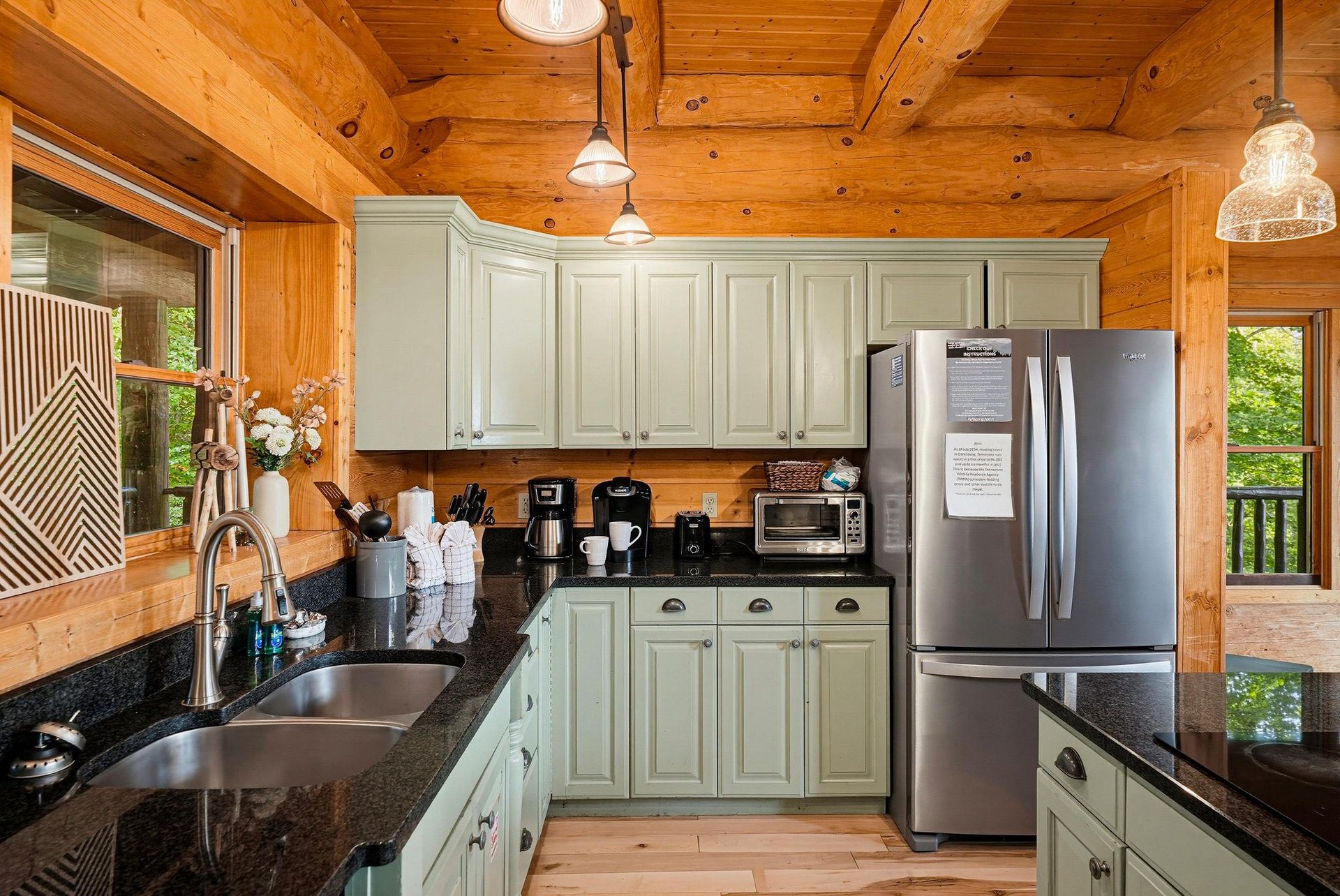 Step into your fully equipped kitchen with warm wood finishes, sage cabinetry, and modern appliances, ready to make meal prep a breeze amid the cozy mountain setting.