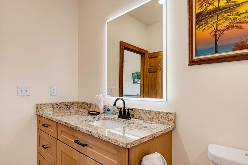 Your private bathroom features a granite vanity, warm wood cabinetry, and bright lighting to start your day refreshed.