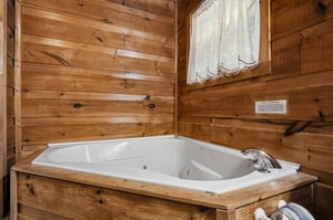Soak your cares away in this inviting jetted tub, surrounded by warm knotty pine walls that create a cozy, cabinlike retreat perfect for unwinding after a day of adventure.