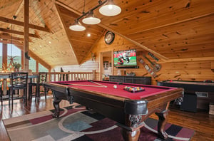 Challenge your companions to a friendly game in your private entertainment loft, where rustic timber beams frame your spirited matches beneath warm pendant lights.