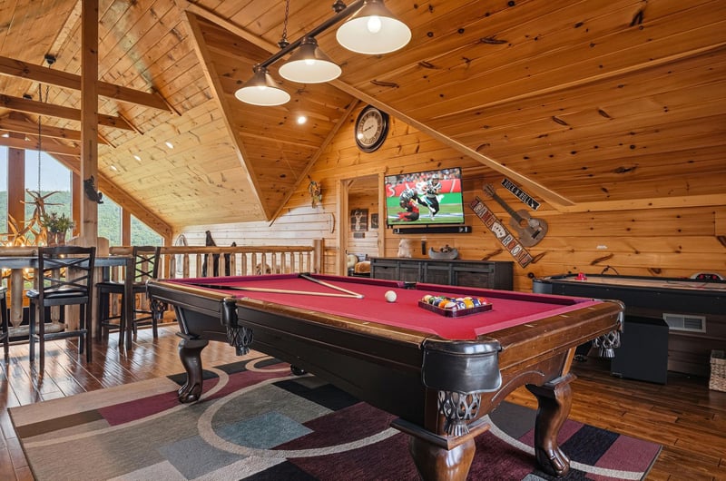 Challenge your companions to a friendly game in your private entertainment loft, where rustic timber beams frame your spirited matches beneath warm pendant lights.