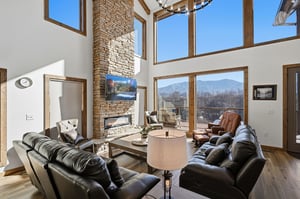 Sink into plush leather seating by the stone fireplace while mountain views frame your perfect retreat through soaring windows.