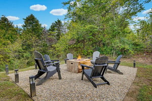 Gather around the fire pit under open skies, where crackling flames and Adirondack chairs set the scene for storytelling and smores beneath the trees.