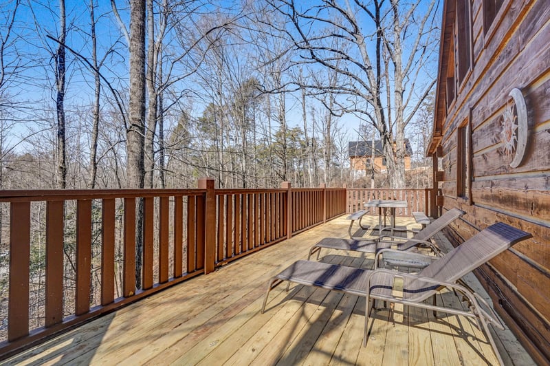 Step onto your private deck where comfortable lounge chairs await, perfect for soaking up mountain sunshine surrounded by peaceful forest views.