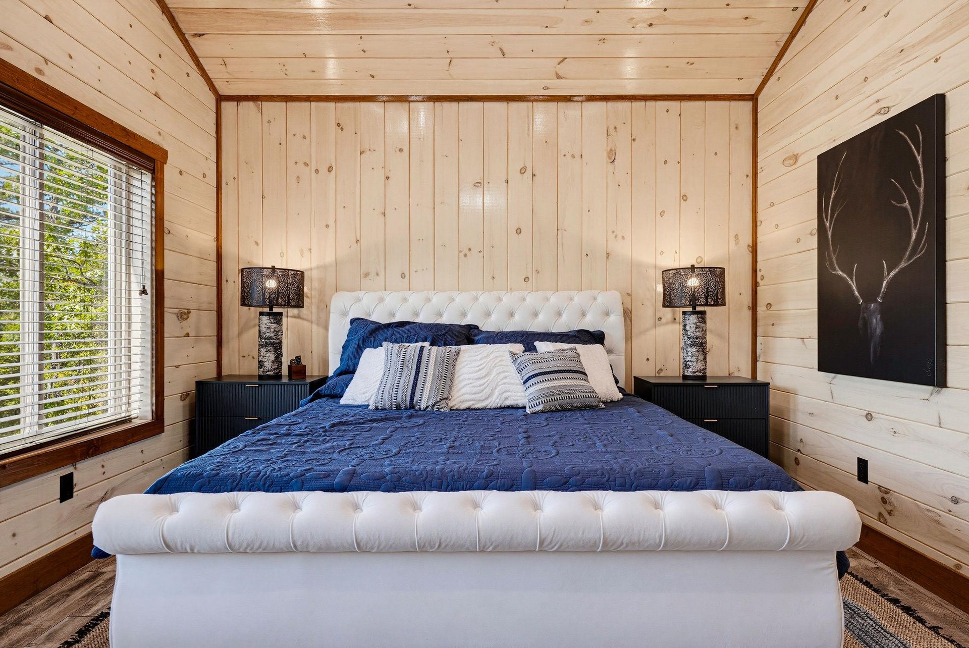 Drift off in your serene bedroom, wrapped in cozy linens on a plush tufted bed, with warm wood paneling and soft lamplight creating the perfect haven for restful nights.