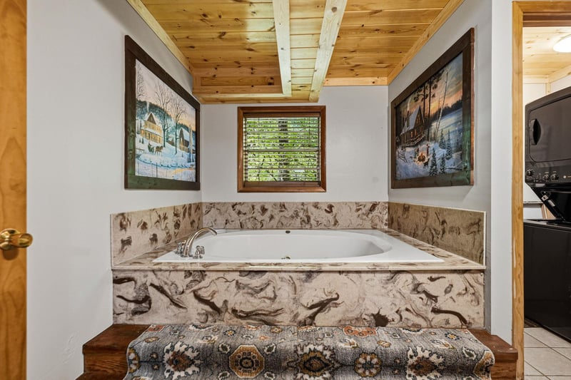 Slip into your private soaking tub beneath warm wood beams and let the day melt away, surrounded by charming artwork and a peaceful view through the window.