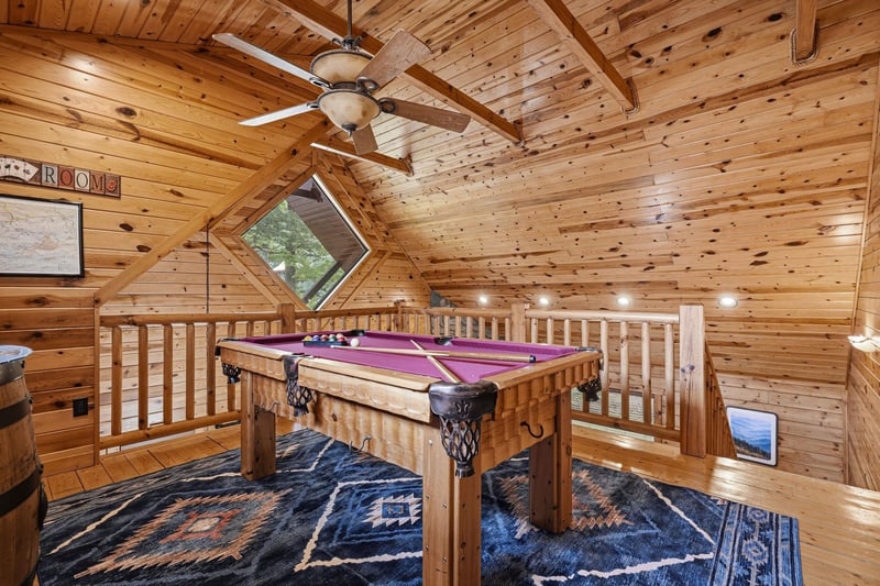 Challenge friends to a game in this cozy loft game room, where rustic charm meets friendly competition under soaring wooden beams.
