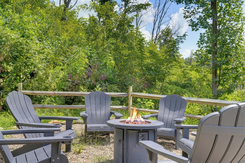 Gather around the fire pit and unwind on this peaceful patio, surrounded by lush greenery and warm summer vibes.