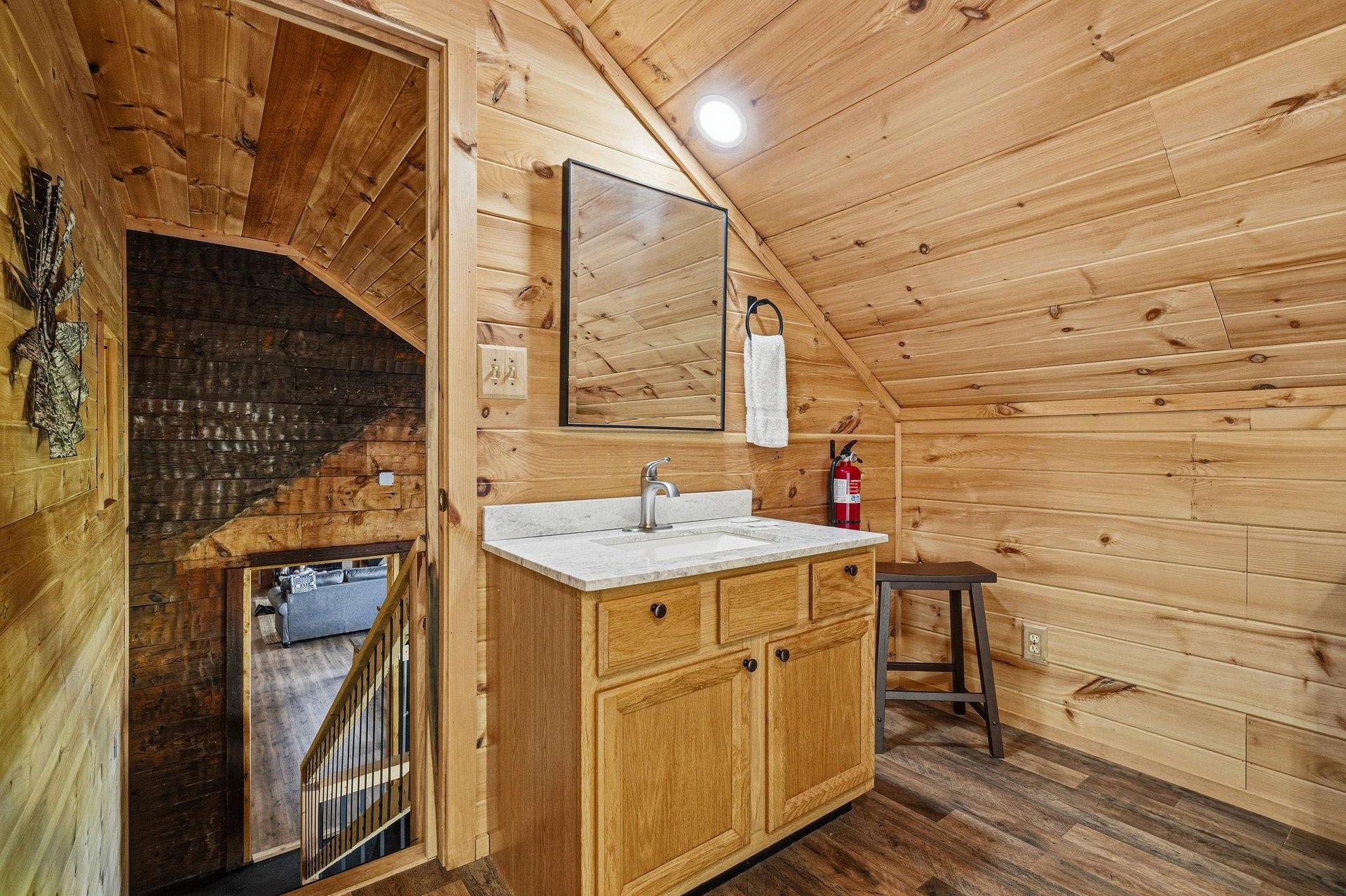 Freshen up at this charming bathroom vanity, tucked under the warm cedar ceiling. The marble countertop and oak cabinetry add rustic elegance, while the mirror and fresh towel make it feel like your p