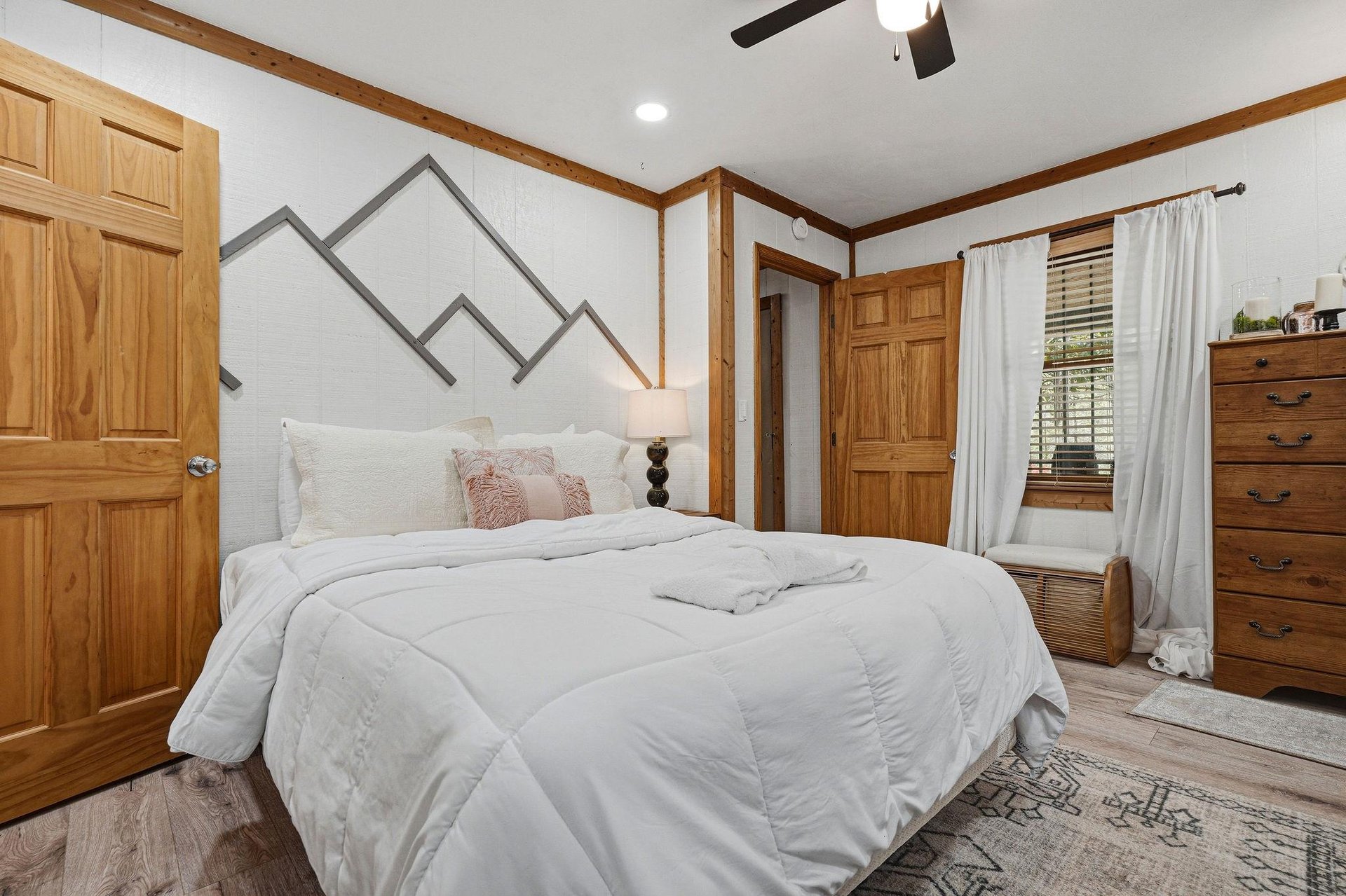 Cozy mountainthemed bedroom with plush white bedding, warm wood accents, and everything you need for a peaceful retreat.