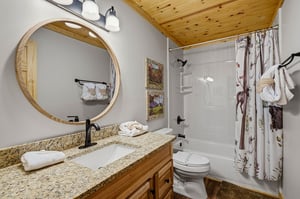 Your private bathroom features granite countertops, a rustic wood vanity, and a charming knotty pine ceiling that adds warmth and mountain charm to your getaway.
