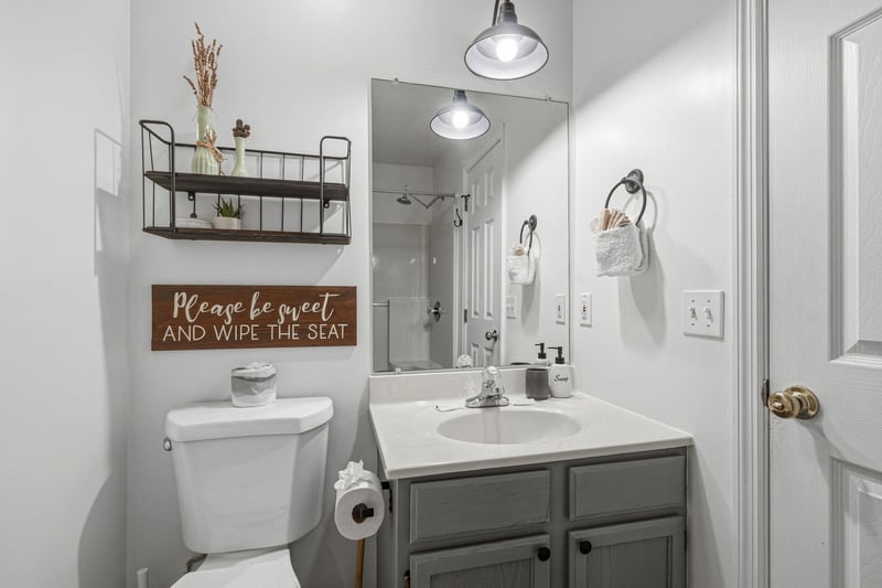 Your private bathroom features a fresh, modern design with thoughtful touches—crisp white linens, stylish lighting, and a charming rustic sign that adds character. Enjoy the clean, relaxing space afte