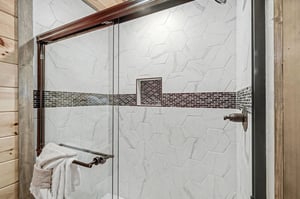 Step into your beautifully tiled shower featuring elegant hexagonal marble with decorative mosaic accents and gleaming fixtures.