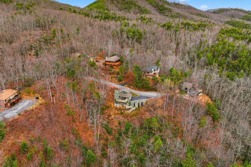 Aerial view of vacation rental properties nestled in the rolling mountains, surrounded by natural forest landscape and seasonal foliage.