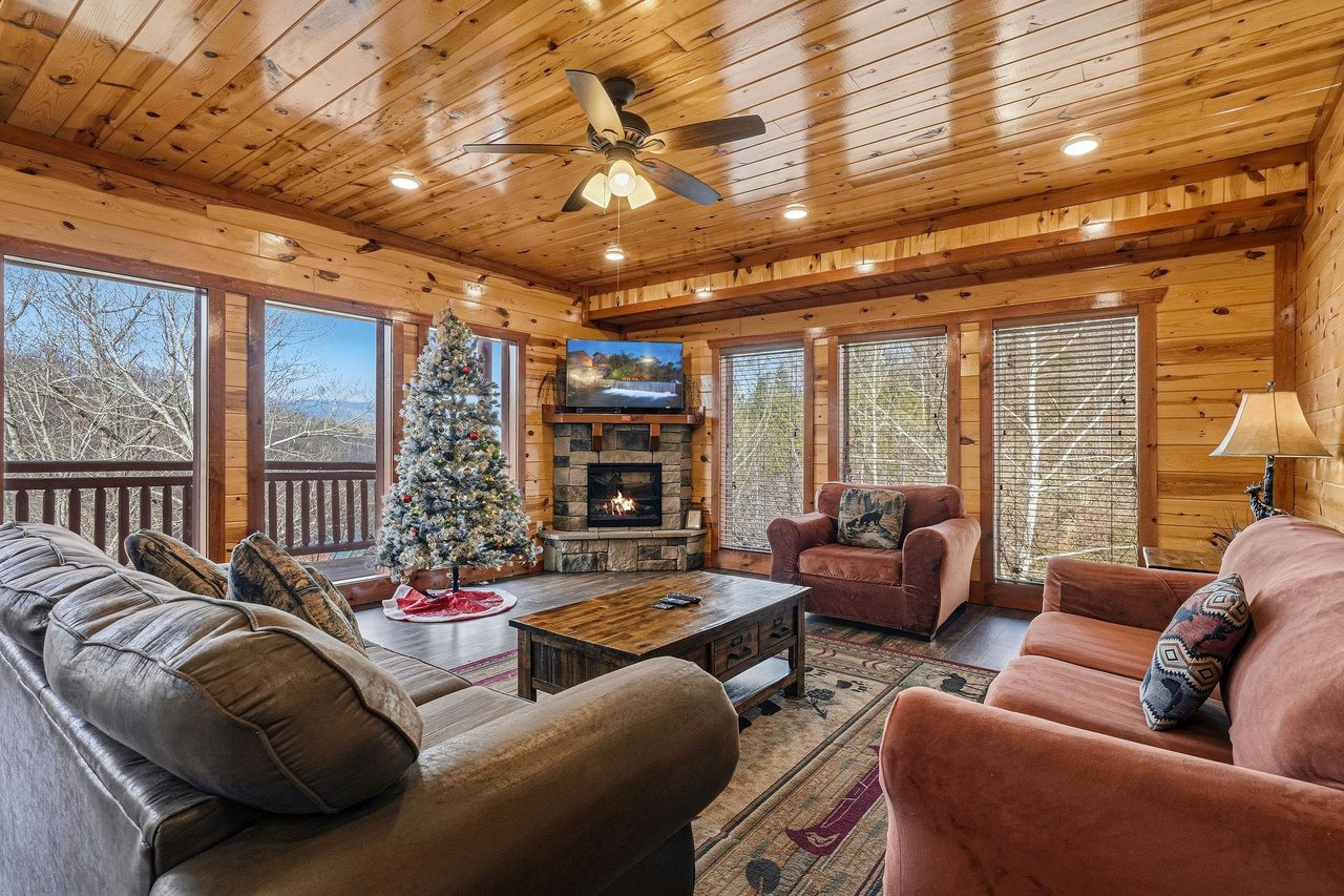 Your cozy cabin living room wraps you in warmth with rustic wood walls, a crackling fireplace, and plush leather seating perfect for mountain relaxation.