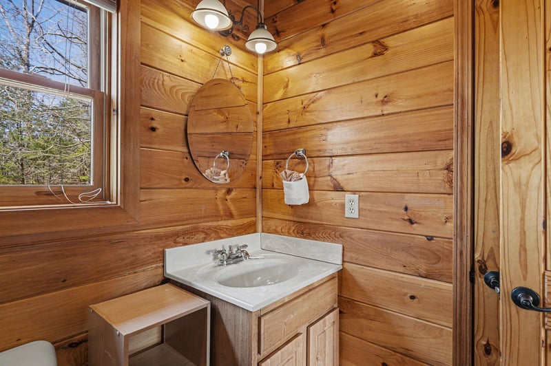 Step into this charming rustic bathroom with warm wood walls, modern fixtures, and natural light streaming in.
