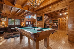 Step into this stunning cabin game room where rustic elegance meets entertainment. Shoot pool under the antler chandelier, unwind on leather sofas, and enjoy the warmth of natural wood surrounding you