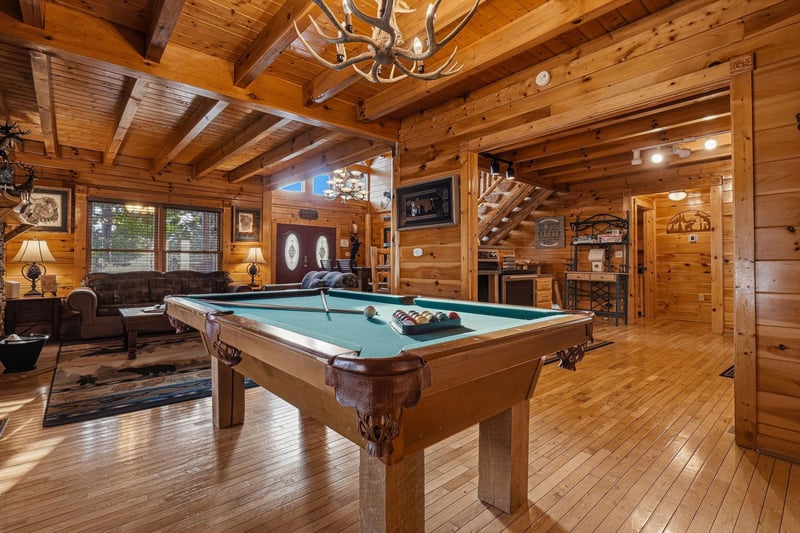 Step into this stunning cabin game room where rustic elegance meets entertainment. Shoot pool under the antler chandelier, unwind on leather sofas, and enjoy the warmth of natural wood surrounding you