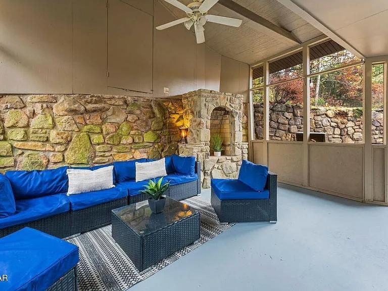 Unwind on your private screened porch with stunning stone fireplace, vibrant blue seating, and peaceful garden views.