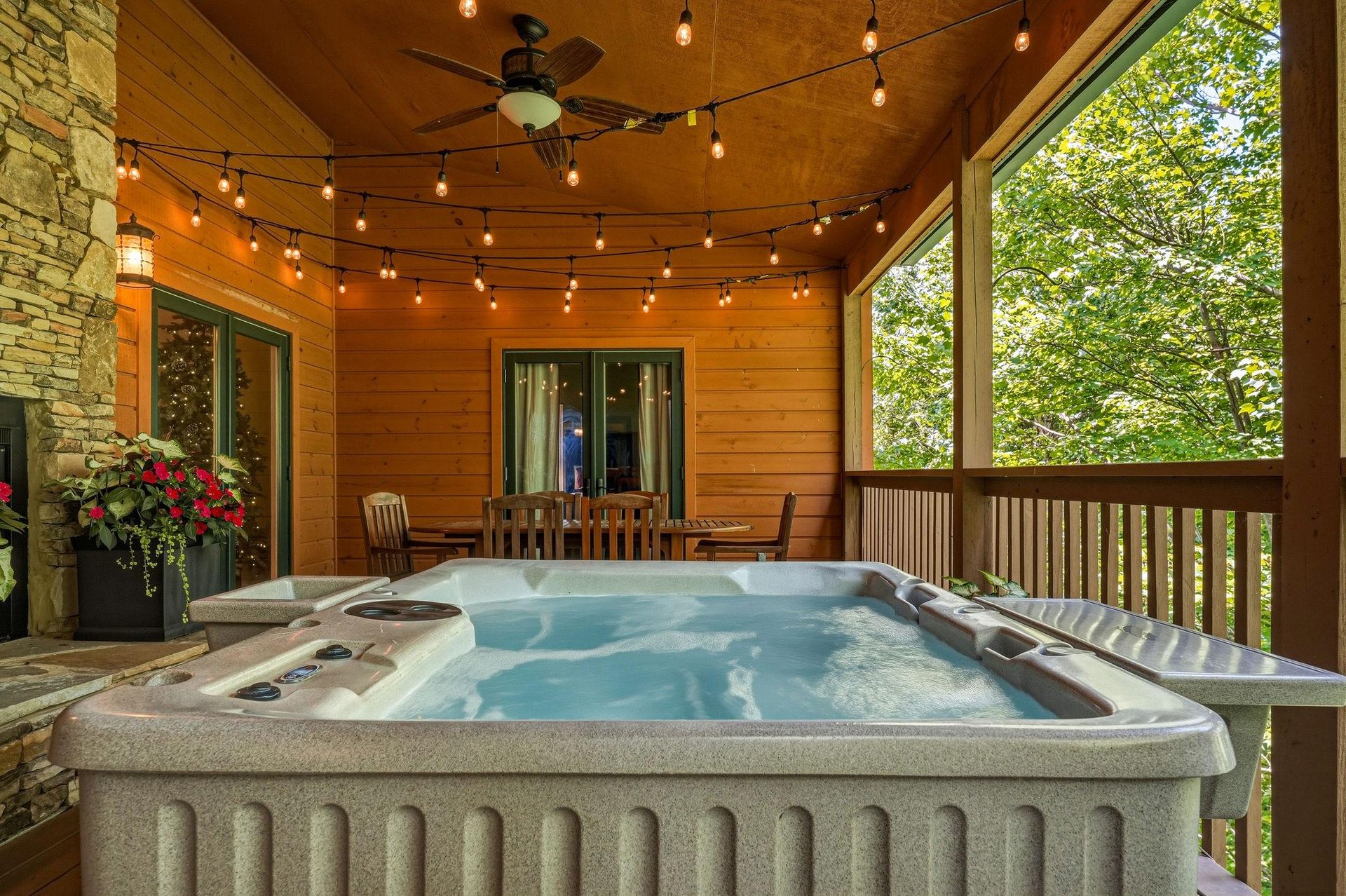 Soak in your private hot tub on this covered porch, surrounded by lush forest views and twinkling lights for cozy evenings under the warm wooden ceiling.