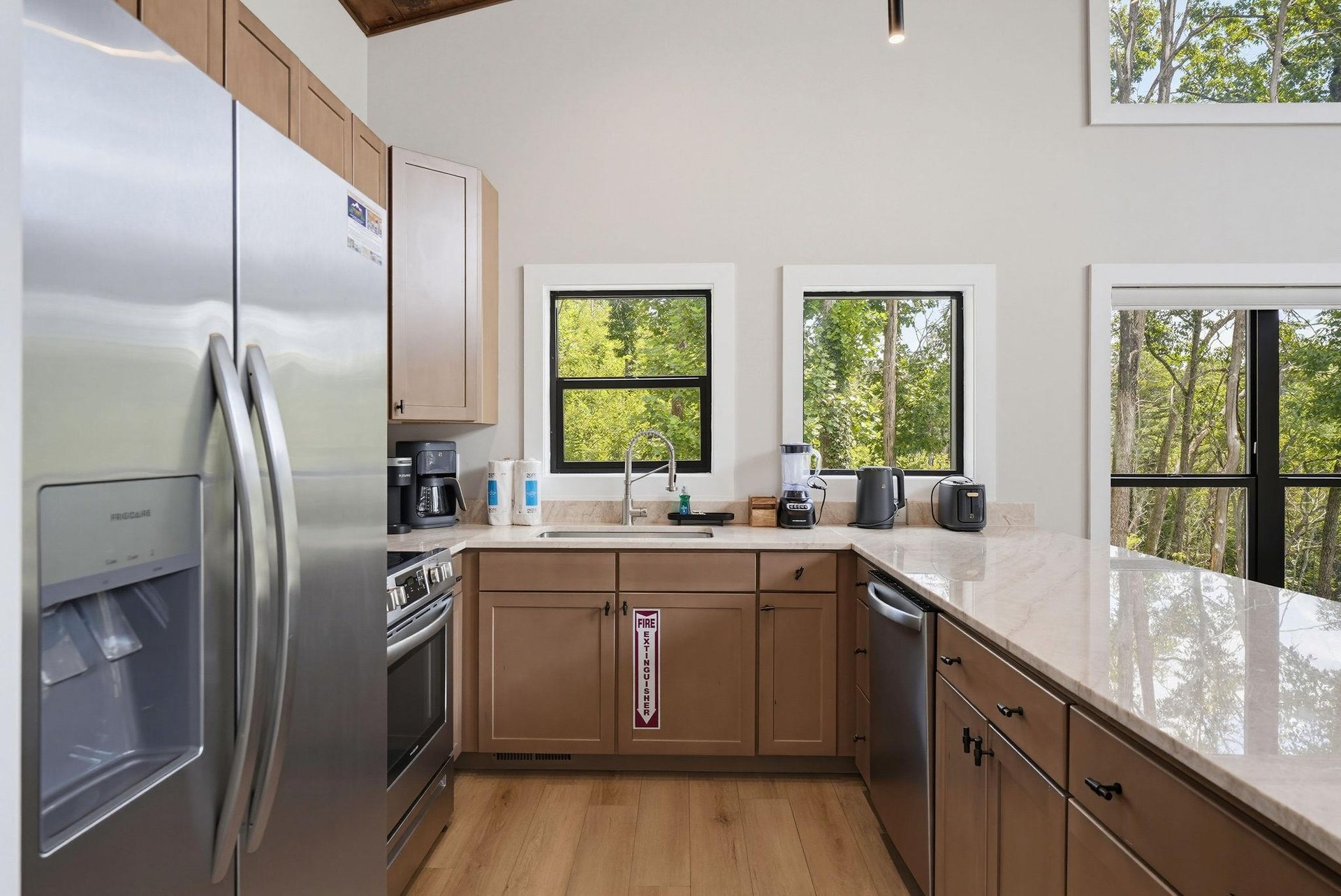 Your fully equipped kitchen features stainless steel appliances, ample counter space, and bright windows framing peaceful tree views—perfect for preparing meals in natural light.