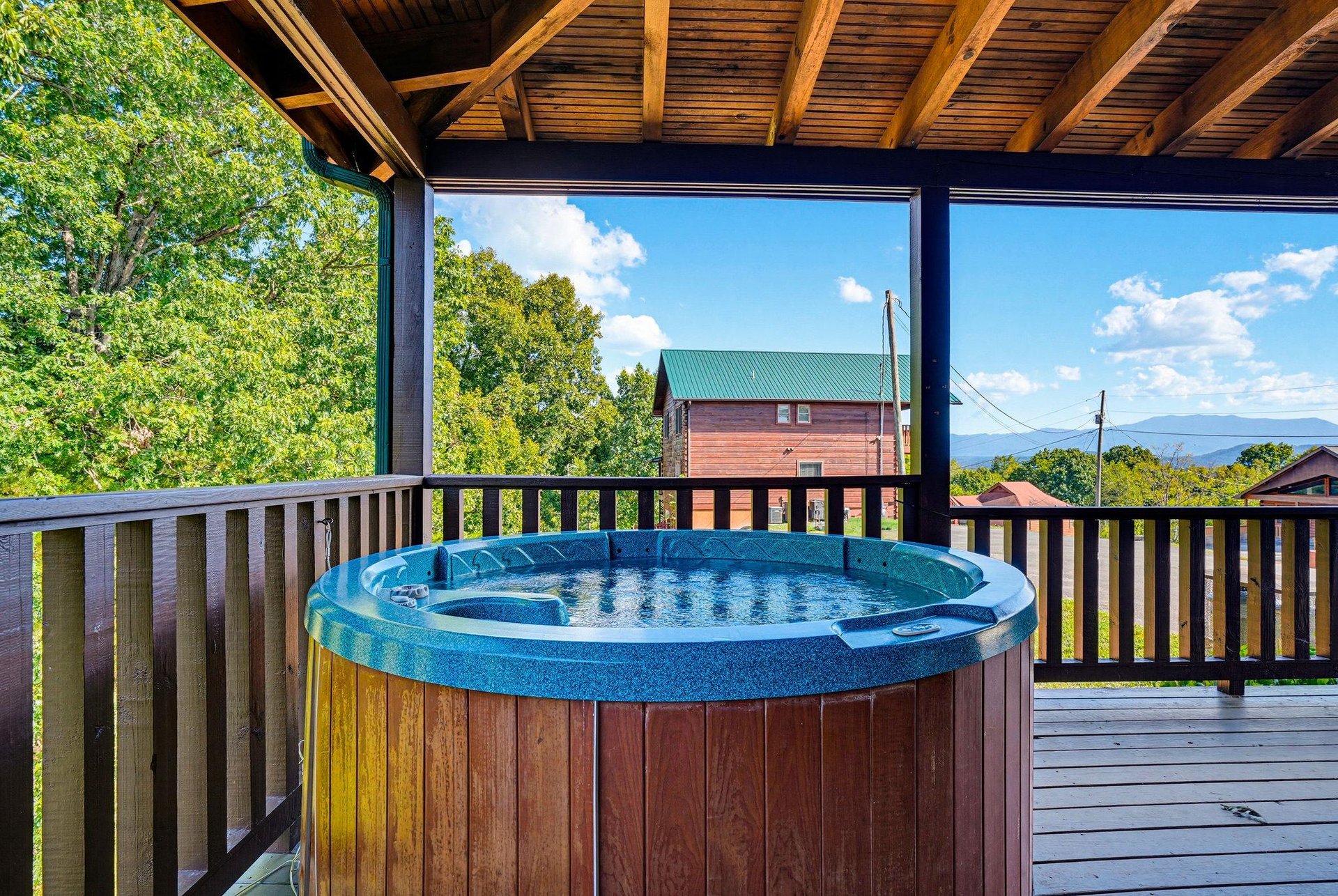 Soak in the hot tub on your private covered deck while enjoying distant mountain views and lush green surroundings—your perfect outdoor escape.