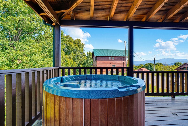 Soak in the hot tub on your private covered deck while enjoying distant mountain views and lush green surroundings—your perfect outdoor escape.