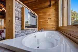 Unwind in your private soaking tub with stunning treetop views through floortoceiling windows. The warm wood paneling and stone fireplace create a cozy retreat for ultimate relaxation.