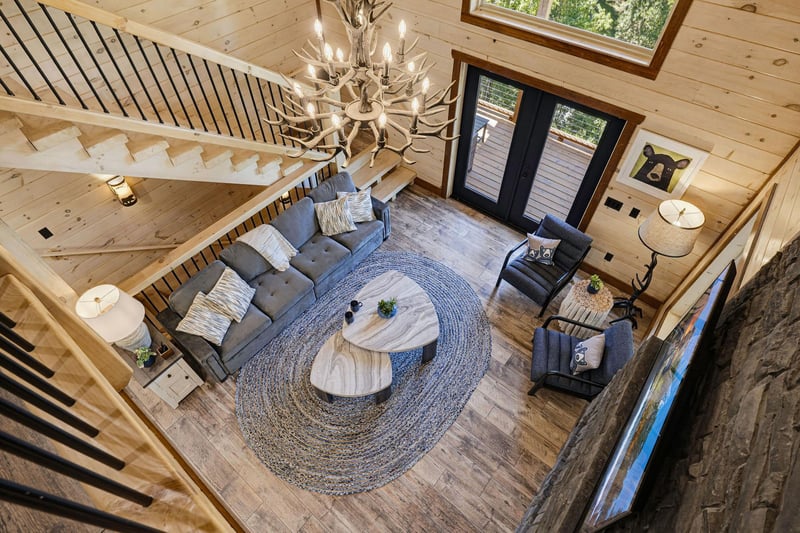 Your charming cabin living room welcomes you with soaring woodpaneled ceilings, a stunning antler chandelier, and cozy seating perfect for gathering after a day of adventure.