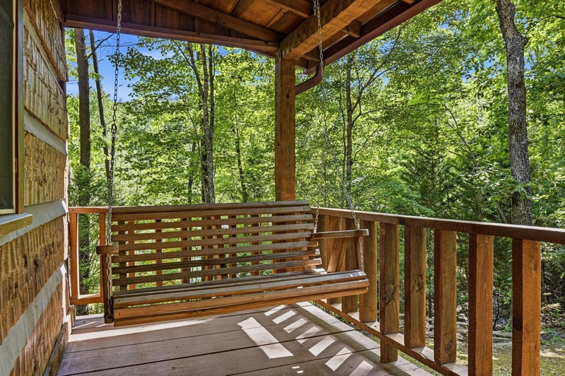 Gently sway on this covered porch swing surrounded by lush forest views—your perfect spot to sip morning coffee or unwind as sunlight filters through the canopy.