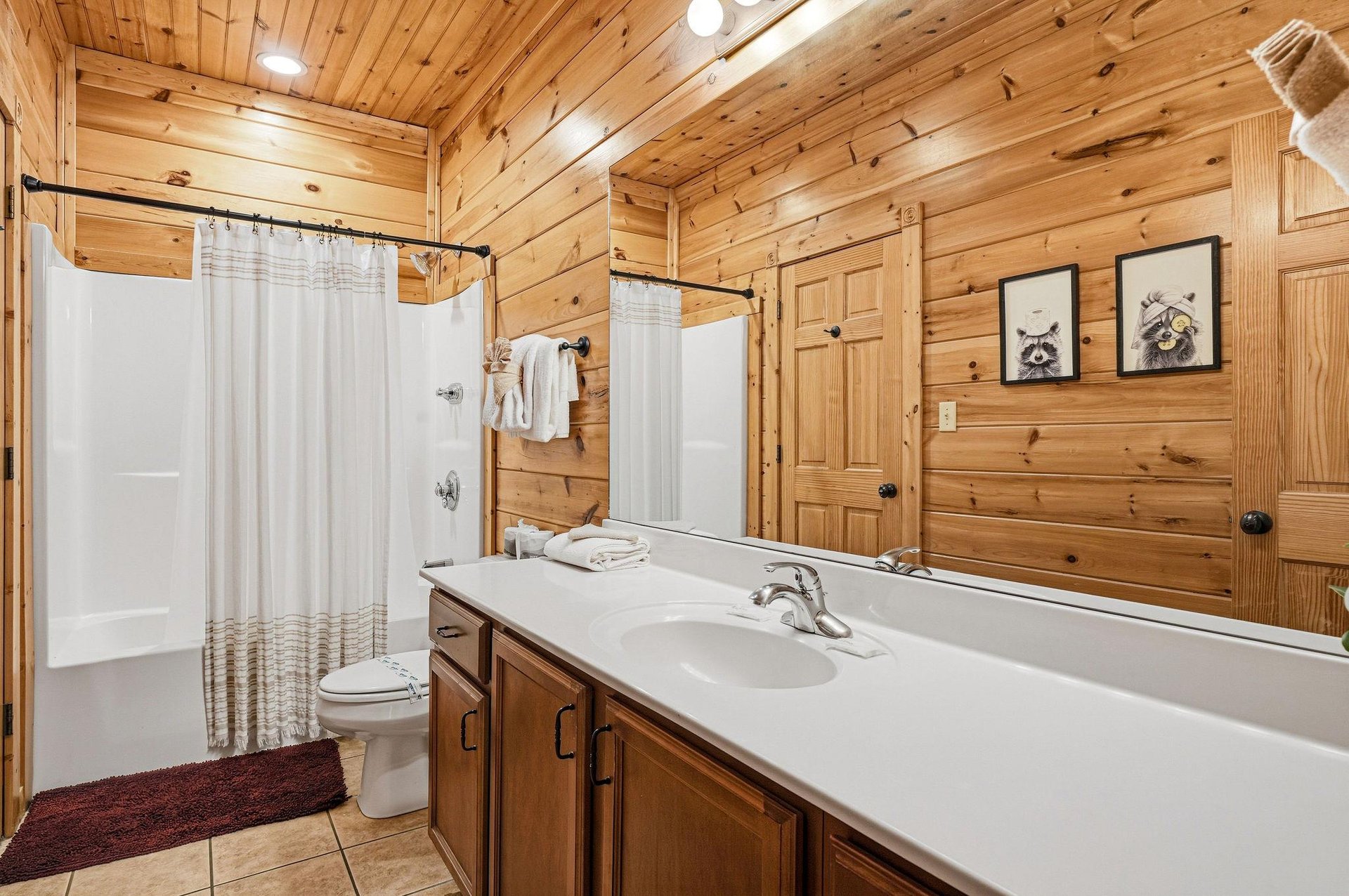Refresh in your rustic bathroom featuring warm wood walls and a spacious showertub combo with fluffy towels waiting for you.