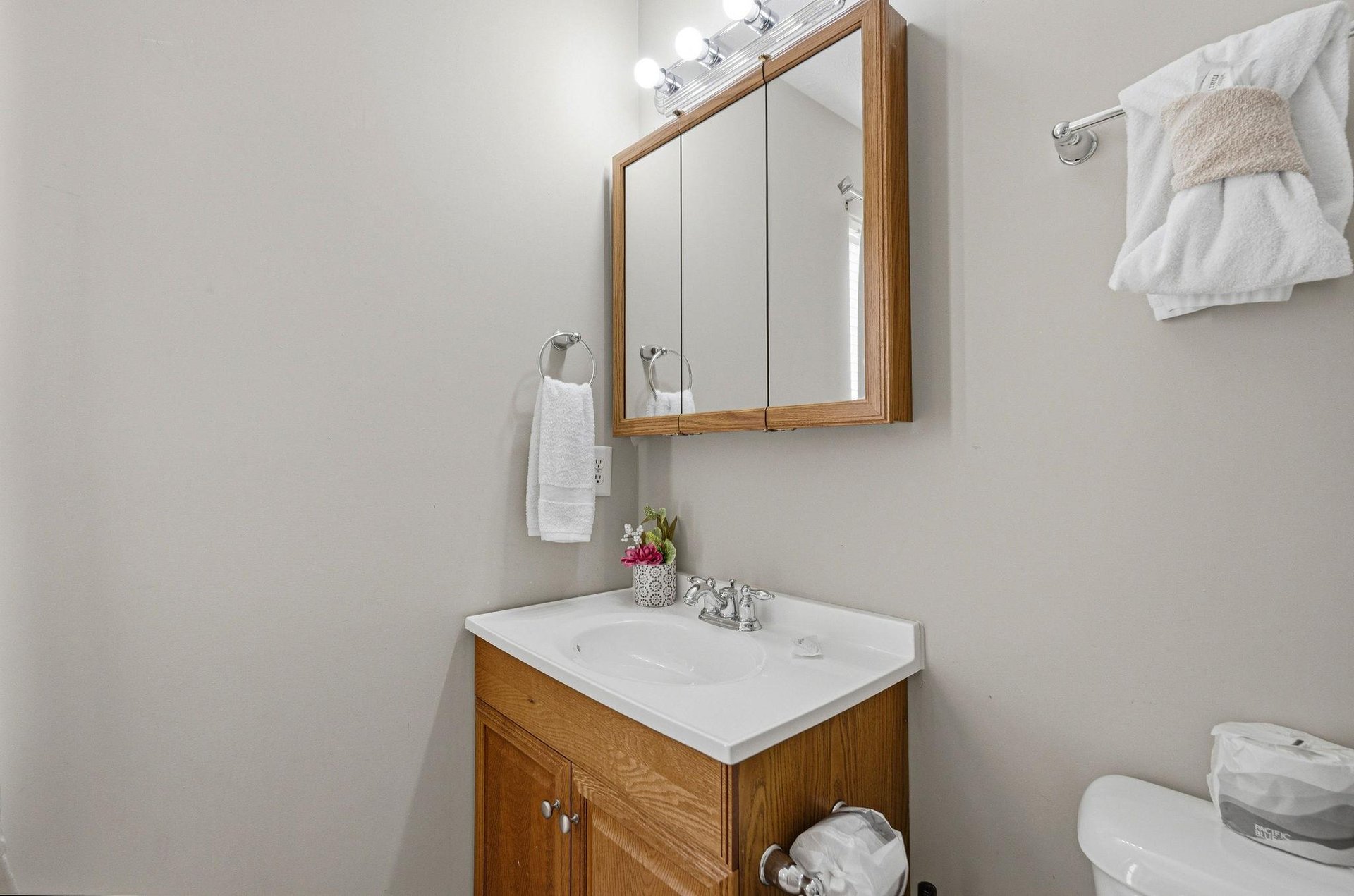 Your private bathroom features warm wood vanity, fresh towels, and thoughtful touches like fresh flowers to make your stay feel special.
