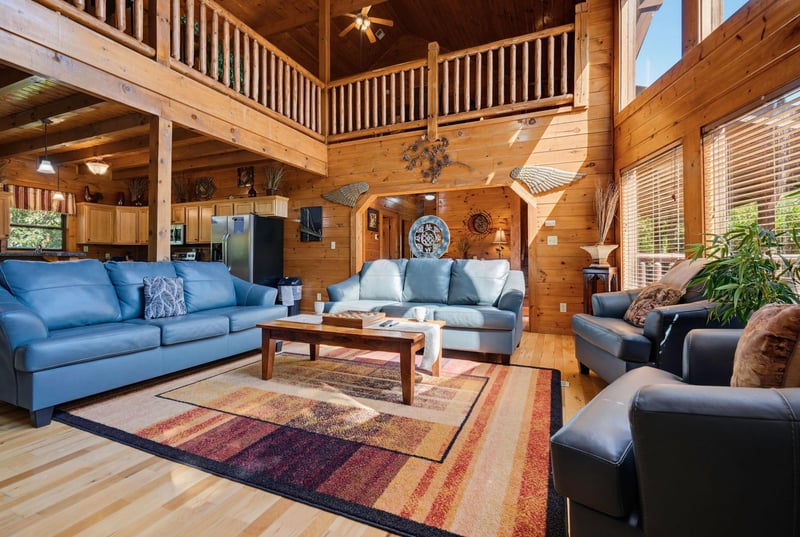Stunning cathedral ceilings and handsome wood beams frame this inviting openplan living space, where you can unwind on plush seating and soak in the cabins warm, rustic charm.