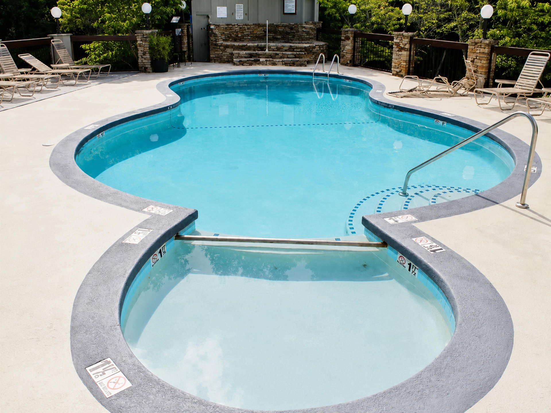 The outdoor pool area at this property, surrounded by sunny lounging spots and natural greenery just beyond the deck.