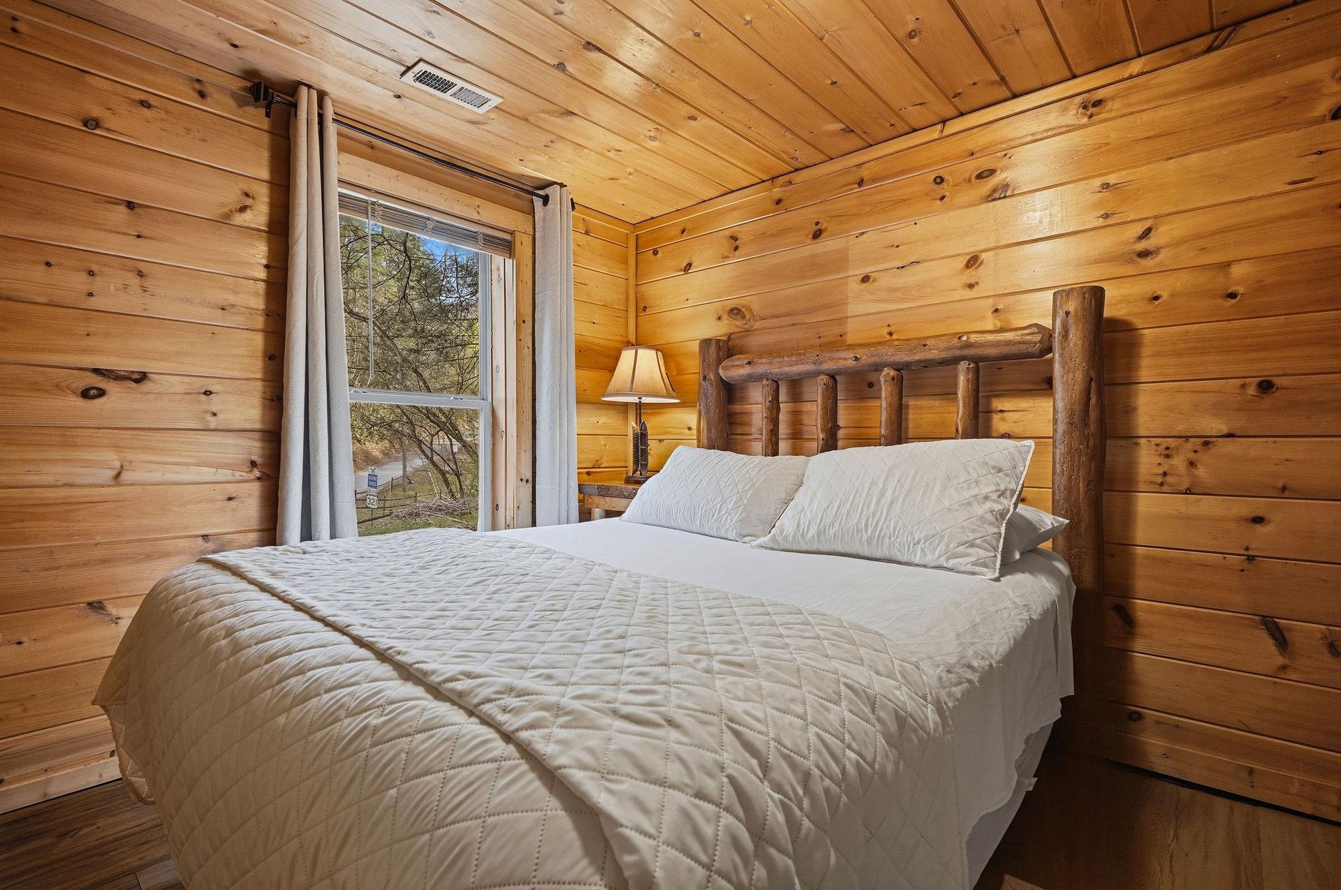 Wake up surrounded by warm knotty pine walls in this cozy log cabin bedroom with rustic charm and peaceful views.