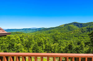 Lush mountain ridges stretch across the horizon under a brilliant blue sky, offering a scenic backdrop to the propertys elevated location.